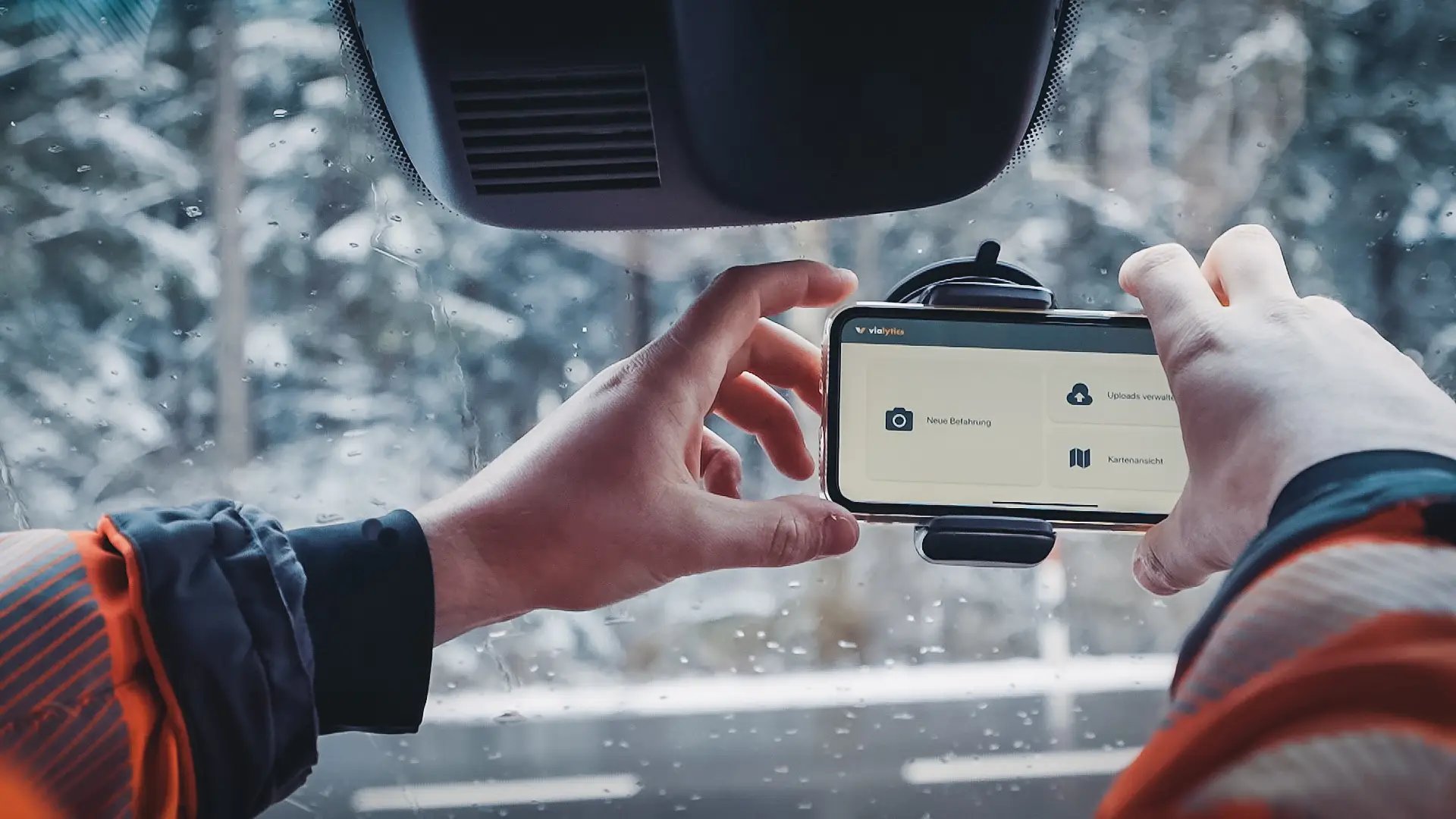 vialytics phone in the windshield on a snowy road being handled by a building yard worker