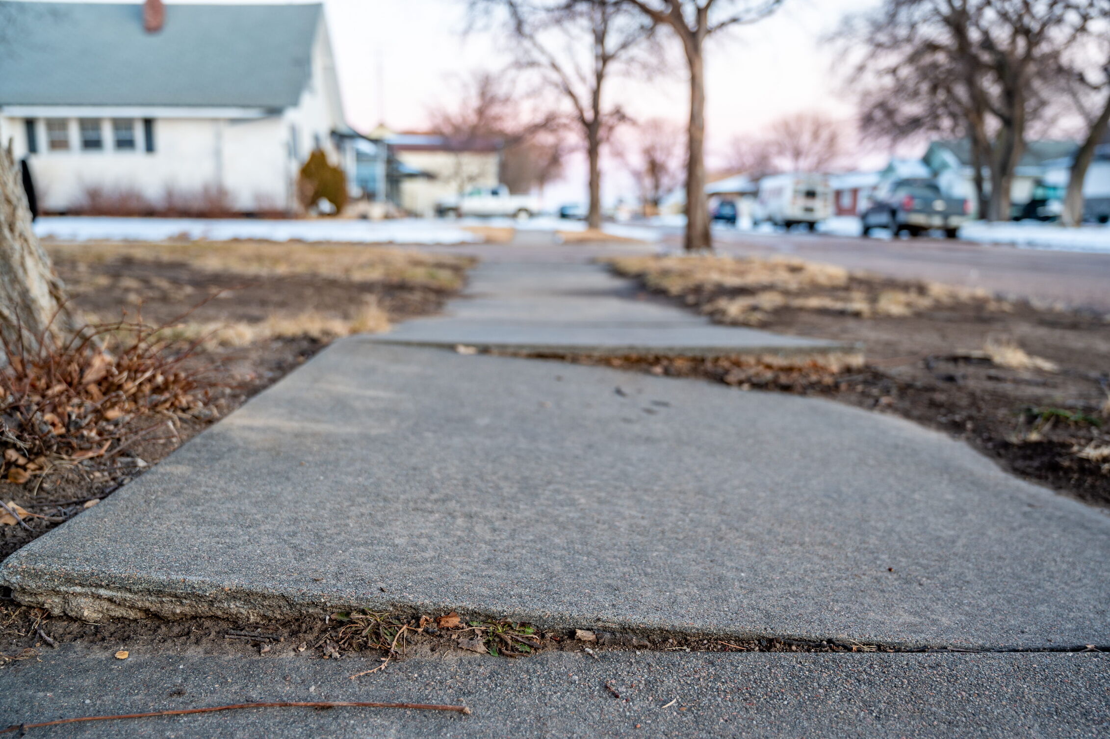 Concrete sidewalk in a residential neighborhood leading toward a house