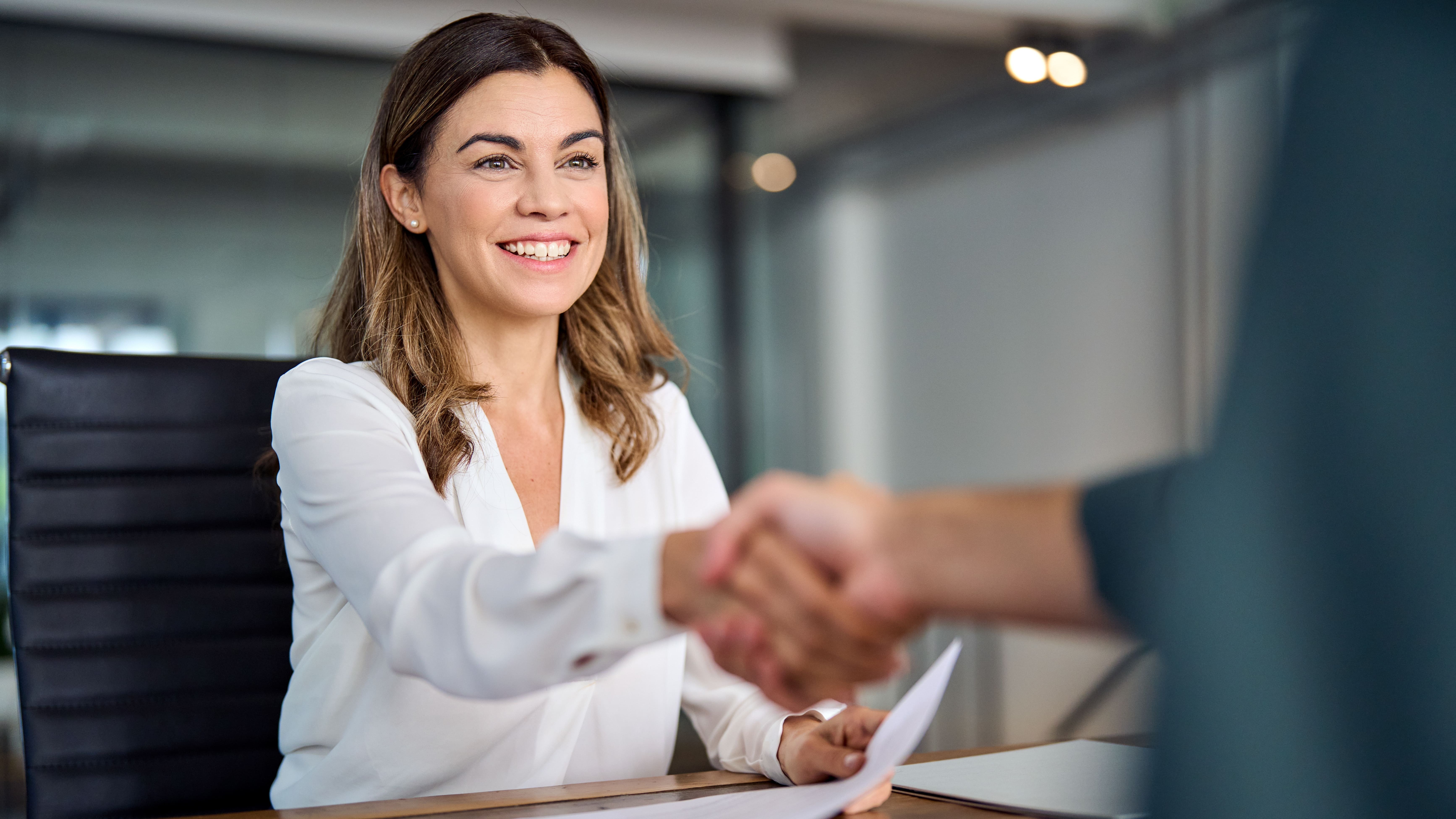 A woman shakes hands with someone. Collaboration between different departments is visualized thanks to vialytics.