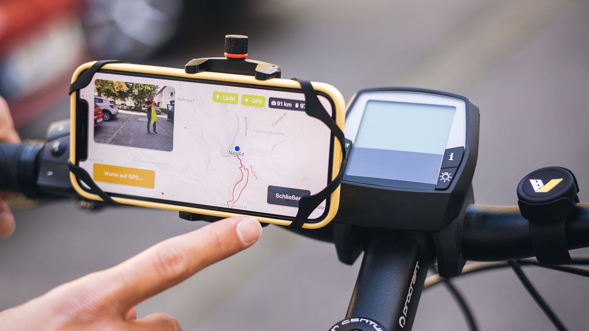 A smartphone in a holder on a bike steering wheel. the road management system is opend an ready to track bicycle paths