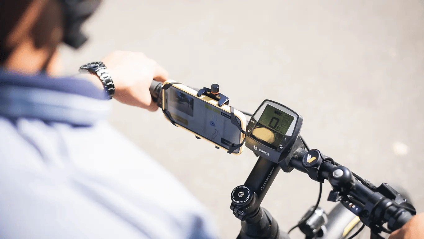 A smartphone in a holder on a bike steering wheel. the road management system is opened an ready to track bicycle paths