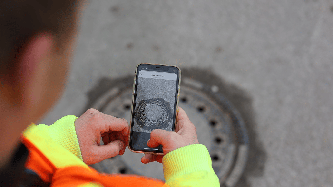 building yard worker takes a picture of a manhole