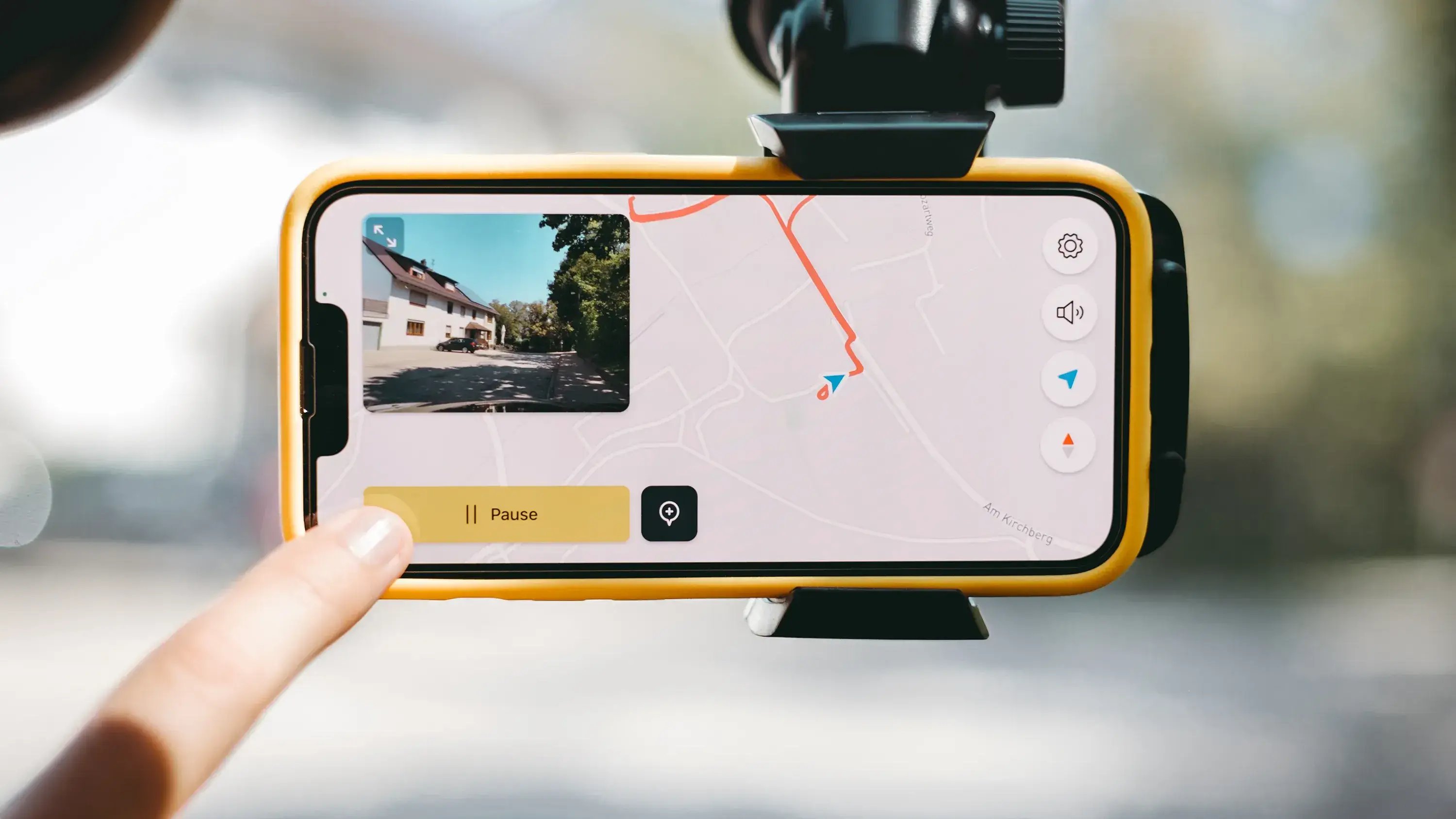A dashboard-mounted smartphone running the vialytics app, displaying a live street camera feed and GPS route map for automated digital route checks and AI damage detection.