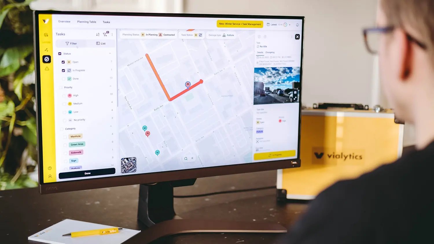An office worker using the vialytics Web System on a large monitor to review map-based analytics for deploying emergency resources and planning recovery efforts.