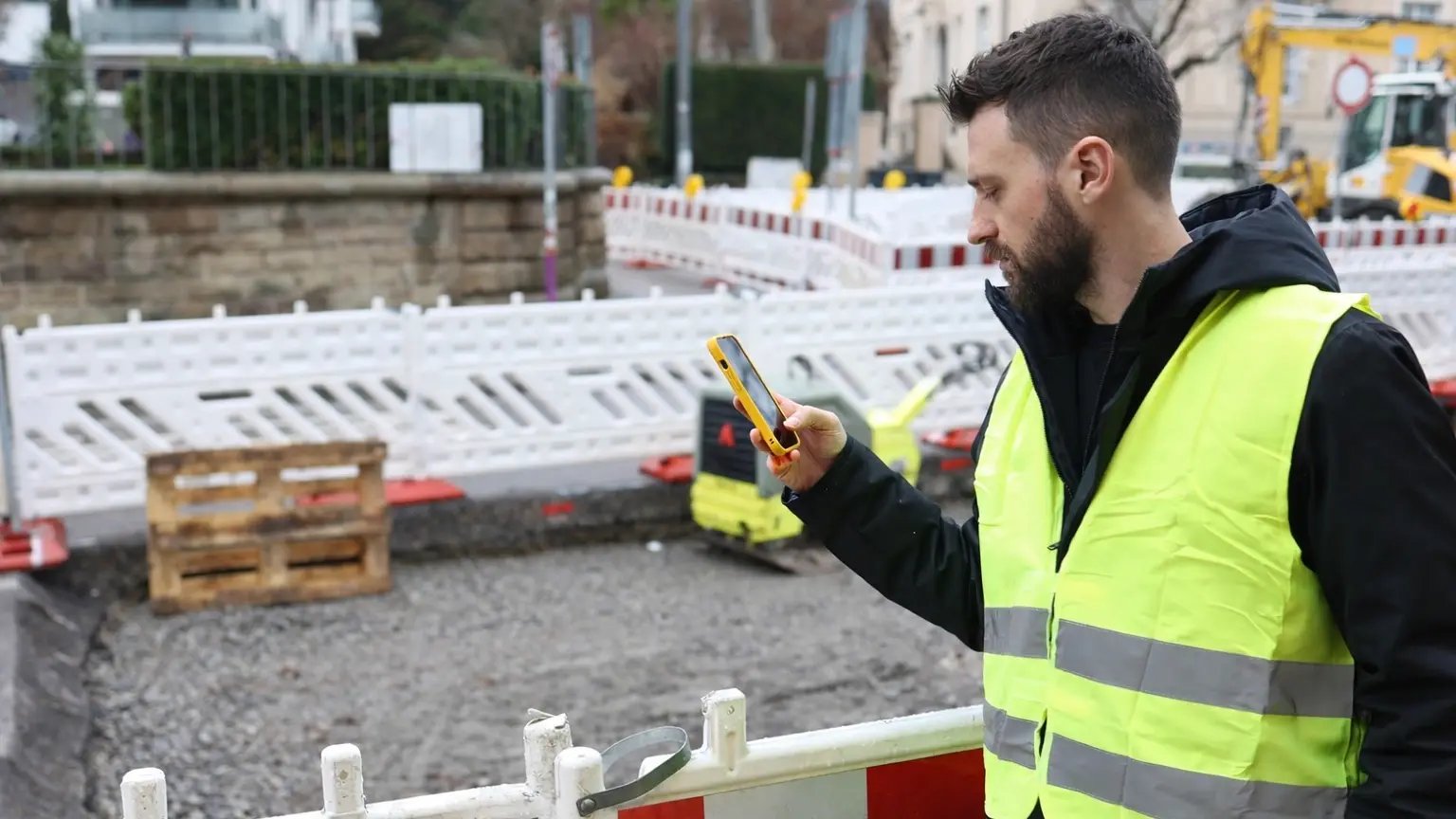Municipal employee using the vialytics mobile app to inspect contractor work at a road construction site