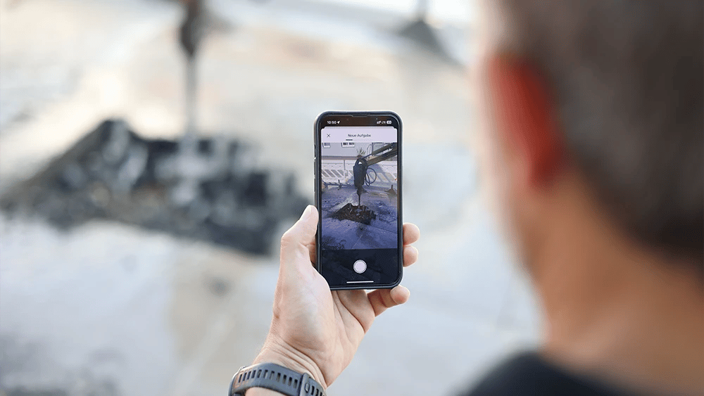 Person using a mobile app to capture a time-stamped image of street repairs for warranty tracking