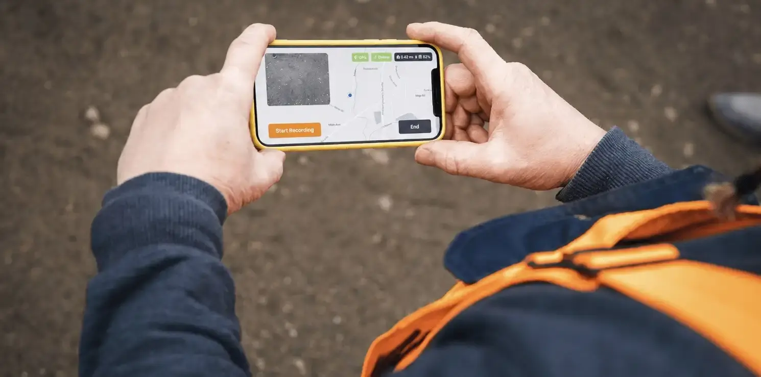 Field worker using a mobile device to photograph and document a sidewalk